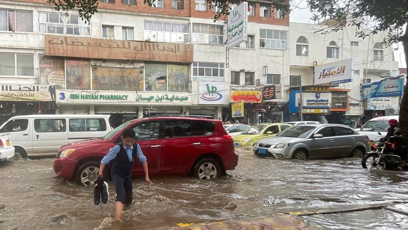 Seorang pria menyeberangi jalan yang banjir saat hujan lebat di Sanaa, Yaman, 28 Agustus 2024. (REUTERS/Khaled Abdullah)