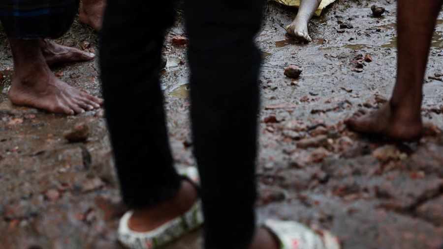 Orang-orang membawa barang-barang mereka untuk menyeberangi jalan yang banjir setelah hujan lebat di Ahmedabad, India, 28 Agustus 2024. (REUTERS/Amit Dave)