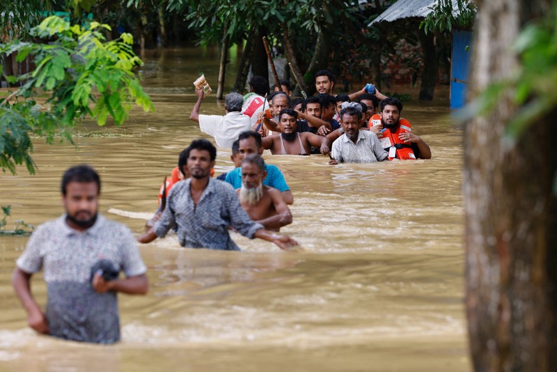 Orang-orang membawa barang-barang mereka untuk menyeberangi jalan yang banjir setelah hujan lebat di Ahmedabad, India, 28 Agustus 2024. Orang-orang membawa barang-barang mereka untuk menyeberangi jalan yang banjir setelah hujan lebat di Ahmedabad, India, 28 Agustus 2024. (REUTERS/Amit Dave)