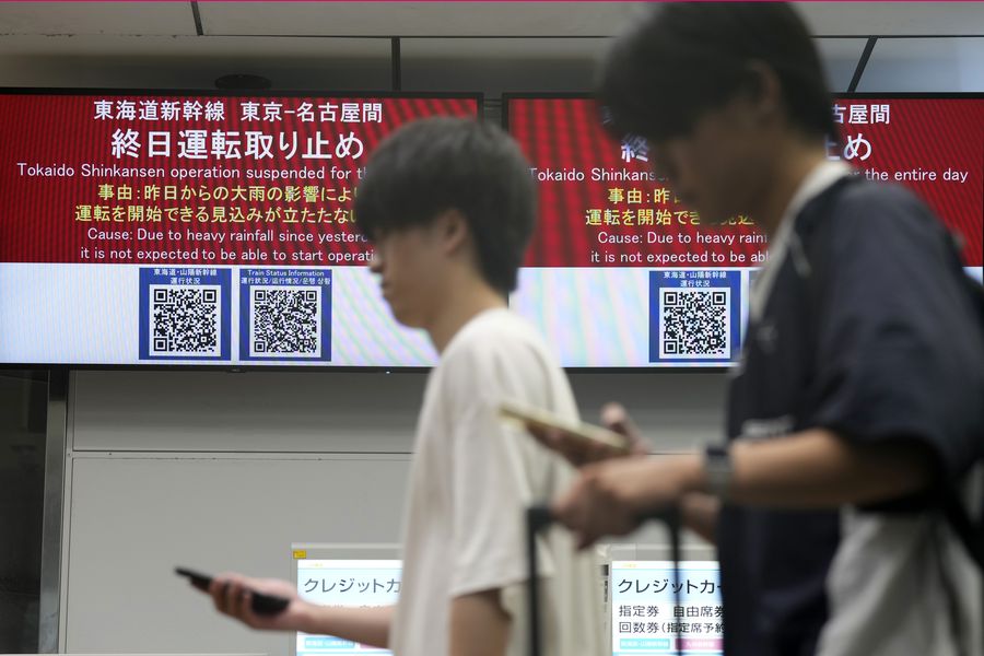 Orang-orang berjalan melewati pemberitahuan bahwa semua kereta Tokaido dan Sanyo Shinkansen menuju Nagoya atau ke arah barat dibatalkan karena hujan lebat yang disebabkan oleh Topan Shanshan di Stasiun Tokyo, Jumat, 30 Agustus 2024, di Tokyo.