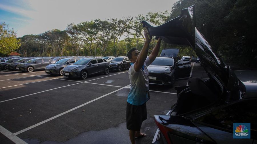 Petugas melihat mobil listrik yang terparkir di area Central Park ITDC Nusa Dua, Badung, Bali, Jumat (30/5/2024). (CNBC Indonesia/Faisal Rahman)
