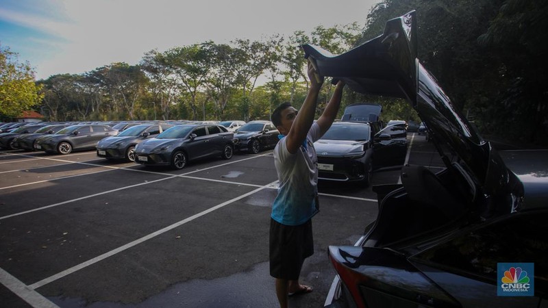 Petugas melihat mobil listrik yang terparkir di area Central Park ITDC Nusa Dua, Badung, Bali, Jumat (30/5/2024). (CNBC Indonesia/Faisal Rahman)
