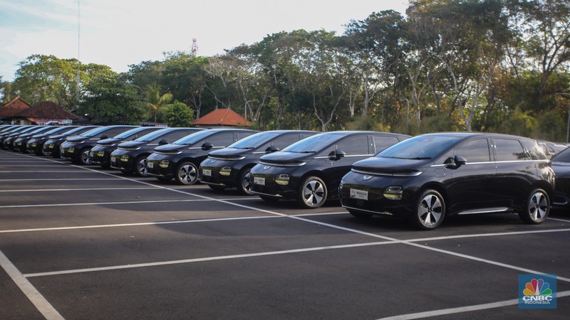 Petugas melihat mobil listrik yang terparkir di area Central Park ITDC Nusa Dua, Badung, Bali, Jumat (30/5/2024). (CNBC Indonesia/Faisal Rahman)