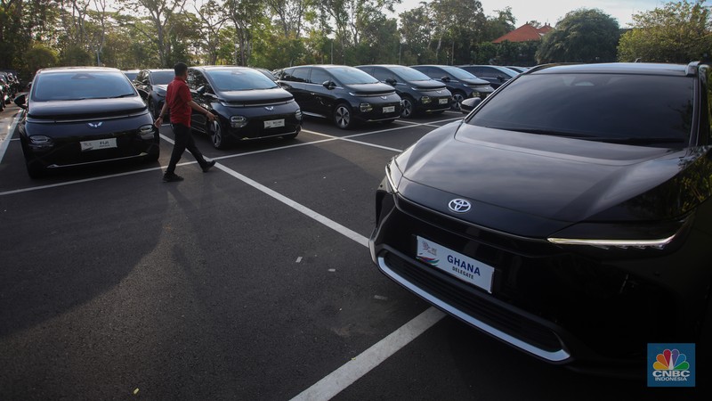 Petugas melihat mobil listrik yang terparkir di area Central Park ITDC Nusa Dua, Badung, Bali, Jumat (30/5/2024). (CNBC Indonesia/Faisal Rahman)