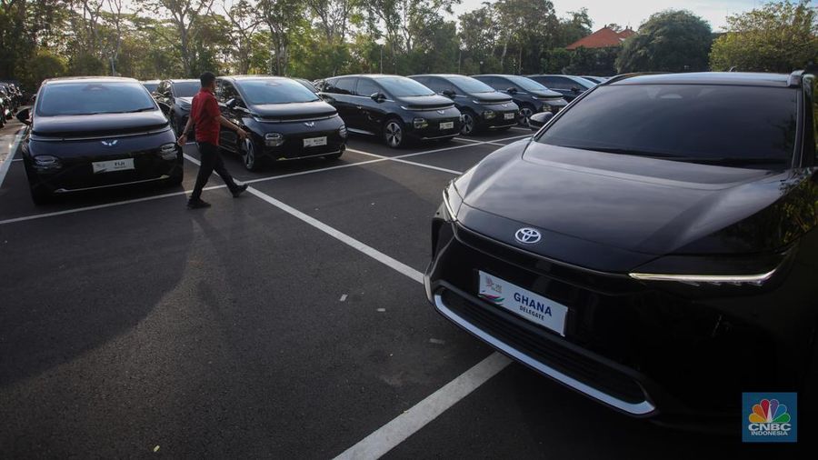 Petugas melihat mobil listrik yang terparkir di area Central Park ITDC Nusa Dua, Badung, Bali, Jumat (30/5/2024). (CNBC Indonesia/Faisal Rahman)