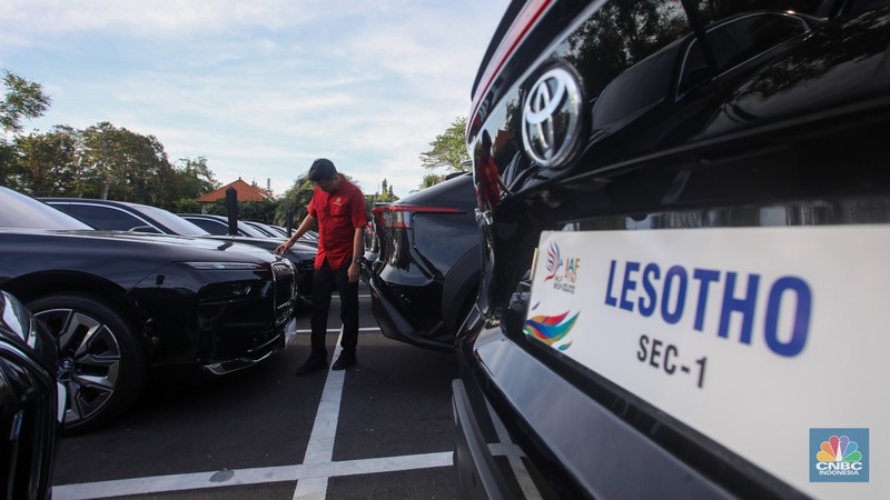 Petugas melihat mobil listrik yang terparkir di area Central Park ITDC Nusa Dua, Badung, Bali, Jumat (30/5/2024). (CNBC Indonesia/Faisal Rahman)