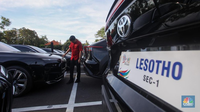 Petugas melihat mobil listrik yang terparkir di area Central Park ITDC Nusa Dua, Badung, Bali, Jumat (30/5/2024). (CNBC Indonesia/Faisal Rahman)