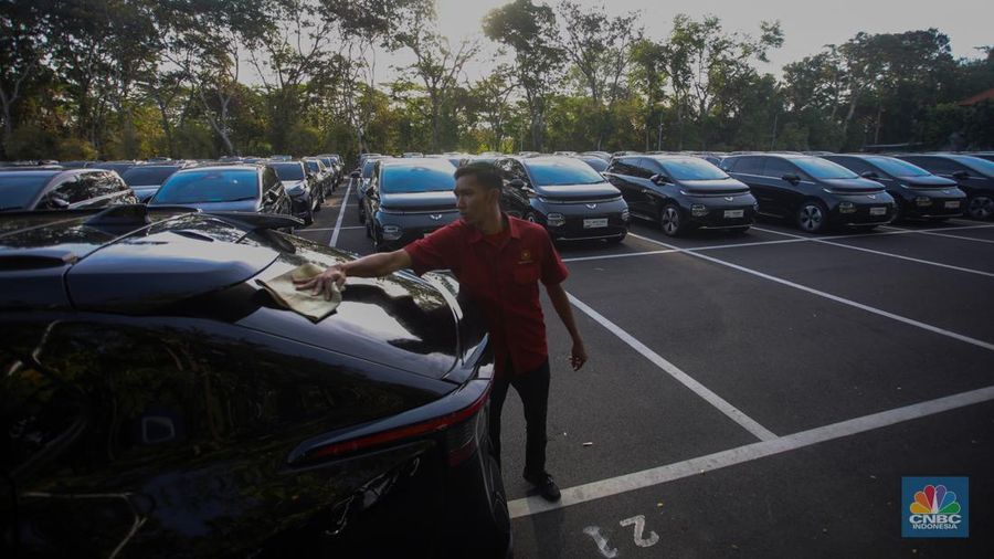 Petugas melihat mobil listrik yang terparkir di area Central Park ITDC Nusa Dua, Badung, Bali, Jumat (30/5/2024). (CNBC Indonesia/Faisal Rahman)