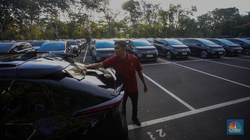 Petugas melihat mobil listrik yang terparkir di area Central Park ITDC Nusa Dua, Badung, Bali, Jumat (30/5/2024). (CNBC Indonesia/Faisal Rahman)
