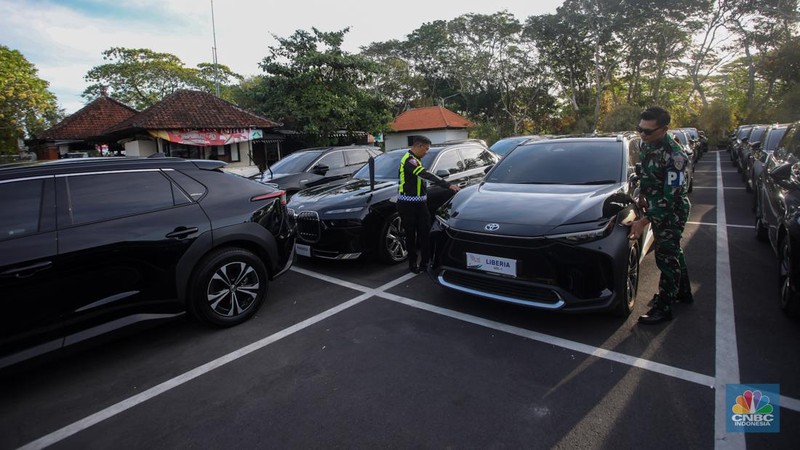 Petugas melihat mobil listrik yang terparkir di area Central Park ITDC Nusa Dua, Badung, Bali, Jumat (30/5/2024). (CNBC Indonesia/Faisal Rahman)
