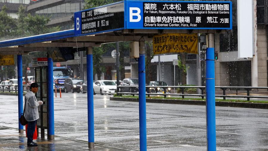 Seorang pria berdiri di halte bus di tengah hujan dan angin yang disebabkan oleh Topan Shanshan di Fukuoka, Jepang, 30 Agustus 2024. (REUTERS/Issei Kato)