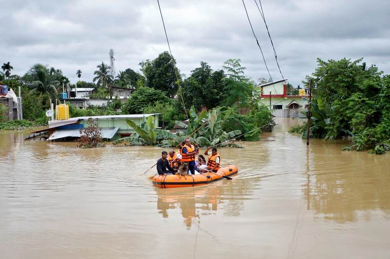 Orang-orang membawa barang-barang mereka untuk menyeberangi jalan yang banjir setelah hujan lebat di Ahmedabad, India, 28 Agustus 2024. Orang-orang membawa barang-barang mereka untuk menyeberangi jalan yang banjir setelah hujan lebat di Ahmedabad, India, 28 Agustus 2024. (REUTERS/Amit Dave)