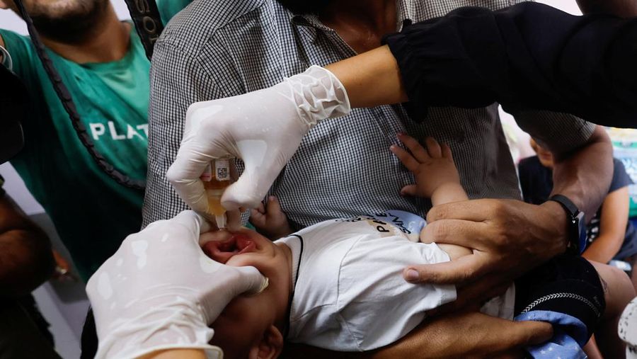 Seorang pria Palestina menggendong seorang anak, saat anak tersebut divaksinasi polio, di tengah konflik Israel-Hamas, di rumah sakit Nasser di Khan Younis di Jalur Gaza selatan, 31 Agustus 2024. (REUTERS/Mohammed Salem)