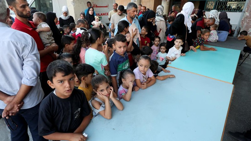 Seorang pria Palestina menggendong seorang anak, saat anak tersebut divaksinasi polio, di tengah konflik Israel-Hamas, di rumah sakit Nasser di Khan Younis di Jalur Gaza selatan, 31 Agustus 2024. (REUTERS/Mohammed Salem)