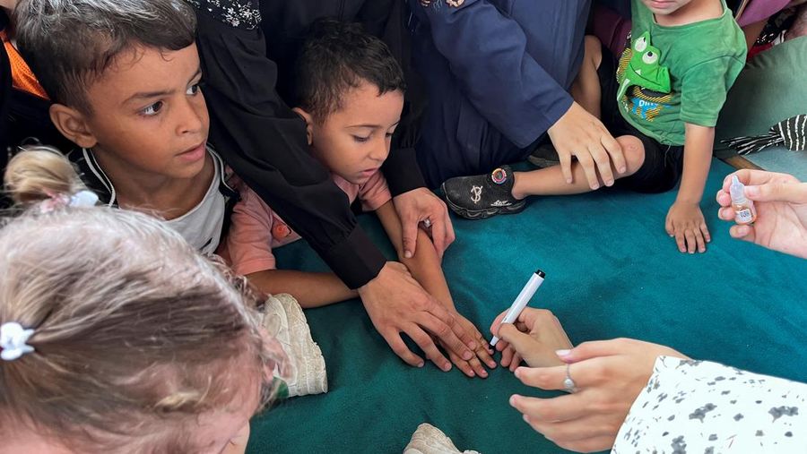 Seorang pria Palestina menggendong seorang anak, saat anak tersebut divaksinasi polio, di tengah konflik Israel-Hamas, di rumah sakit Nasser di Khan Younis di Jalur Gaza selatan, 31 Agustus 2024. (REUTERS/Mohammed Salem)