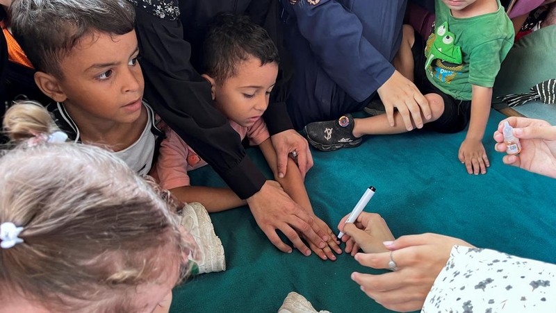 Seorang pria Palestina menggendong seorang anak, saat anak tersebut divaksinasi polio, di tengah konflik Israel-Hamas, di rumah sakit Nasser di Khan Younis di Jalur Gaza selatan, 31 Agustus 2024. (REUTERS/Mohammed Salem)