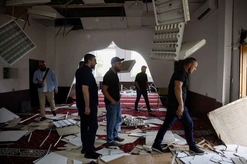 Anggota komunitas Muslim memeriksa kerusakan di masjid Asosiasi Muslim Ukraina, akibat serangan rudal Rusia yang menghancurkan bangunan di sebelahnya, di tengah konflik Rusia-Ukraina, di Kyiv, Ukraina, 2 September 2024. (REUTERS/Thomas Peter)
