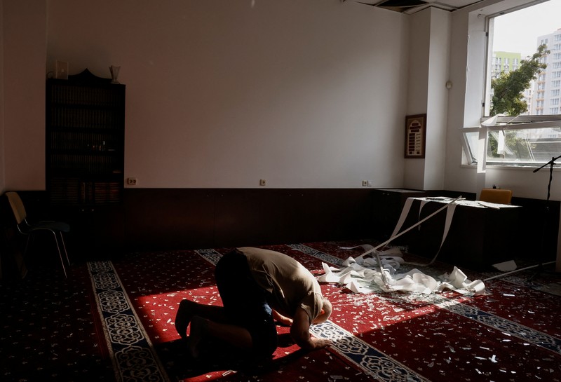 Anggota komunitas Muslim memeriksa kerusakan di masjid Asosiasi Muslim Ukraina, akibat serangan rudal Rusia yang menghancurkan bangunan di sebelahnya, di tengah konflik Rusia-Ukraina, di Kyiv, Ukraina, 2 September 2024. (REUTERS/Thomas Peter)