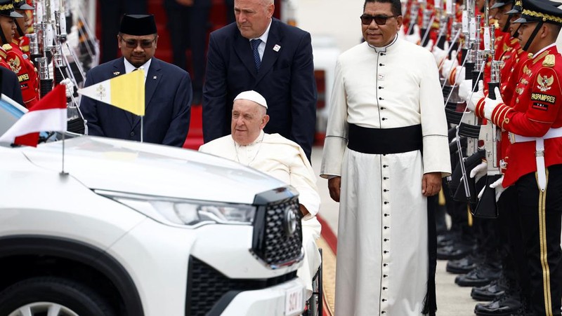 Paus Fransiskus di kursi rodanya, melambaikan tangan saat tiba selama upacara penyambutan resmi di Bandara Internasional Soekarno-Hatta di Tangerang di pinggiran Jakarta, Indonesia, Selasa, 3 September 2024. (AP Photo/Achmad Ibrahim)