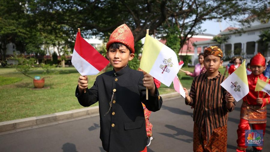 Paus Fransiskus disambut oleh anak-anak yang berpakaian adat Nusantara dengan memegang bendera Merah Putih dan bendera Vatikan di Istana Negara, Jakarta, Selasa (4/9/2024). (CNBC Indonesia/Tri Susilo)