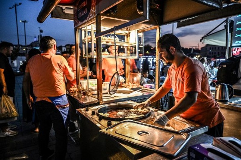 TURKEY-ECONOMY-INFLATION A street vendor sells corn in the Eminonu district of Istanbul on August 29, 2024. In Istanbul, street vendors, popular figures inherited from the Ottoman Empire, are brooding over the loss of a large part of their Turkish clientele, stunned by inflation. (Photo by Ozan KOSE / AFP)