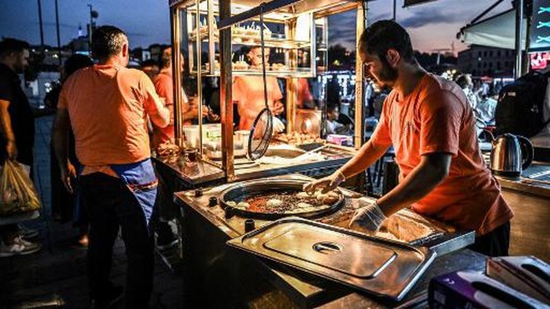 A street vendor sells corn in the Eminonu district of Istanbul on August 29, 2024. In Istanbul, street vendors, popular figures inherited from the Ottoman Empire, are brooding over the loss of a large part of their Turkish clientele, stunned by inflation. (Photo by Ozan KOSE / AFP)