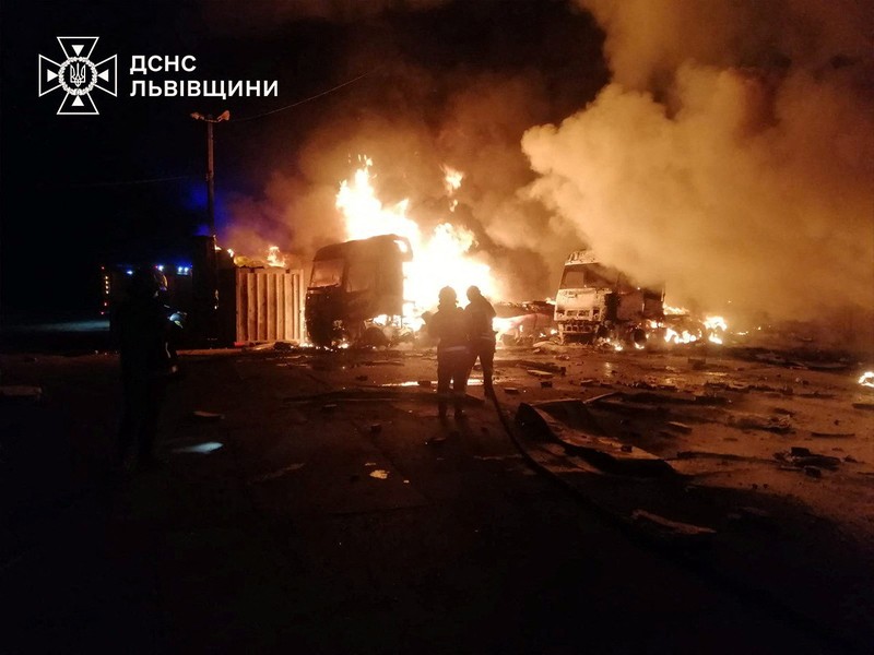 Api dan asap mengepul dari truk yang terbakar di lokasi fasilitas gudang yang terkena serangan pesawat tak berawak Rusia, di tengah serangan Rusia terhadap Ukraina, di desa Murovane, di luar Lviv, Ukraina, 6 September 2024. (Press service of the State Emergency Service of Ukraine/Handout via REUTERS)