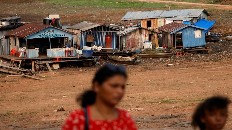 Orang-orang melihat di dekat rumah-rumah terapung yang terdampar akibat kekeringan yang melanda Rio Negro, anak sungai kiri terbesar dari Sungai Amazon, di distrik Cacau Pirera di Iranduba, negara bagian Amazonas, Brasil, 2 September 2024. (REUTERS/Bruno Kelly)