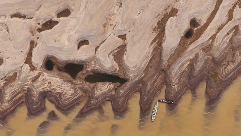 Orang-orang melihat di dekat rumah-rumah terapung yang terdampar akibat kekeringan yang melanda Rio Negro, anak sungai kiri terbesar dari Sungai Amazon, di distrik Cacau Pirera di Iranduba, negara bagian Amazonas, Brasil, 2 September 2024. (REUTERS/Bruno Kelly)