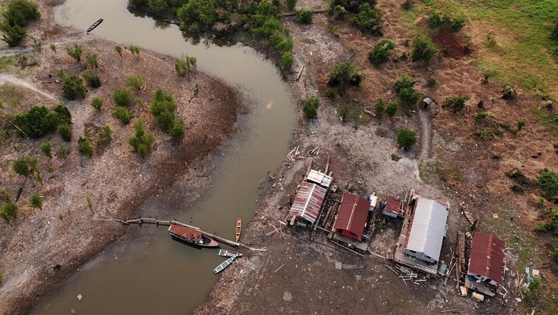 Orang-orang melihat di dekat rumah-rumah terapung yang terdampar akibat kekeringan yang melanda Rio Negro, anak sungai kiri terbesar dari Sungai Amazon, di distrik Cacau Pirera di Iranduba, negara bagian Amazonas, Brasil, 2 September 2024. (REUTERS/Bruno Kelly)