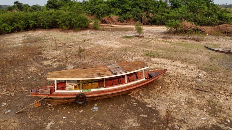 Orang-orang melihat di dekat rumah-rumah terapung yang terdampar akibat kekeringan yang melanda Rio Negro, anak sungai kiri terbesar dari Sungai Amazon, di distrik Cacau Pirera di Iranduba, negara bagian Amazonas, Brasil, 2 September 2024. (REUTERS/Bruno Kelly)