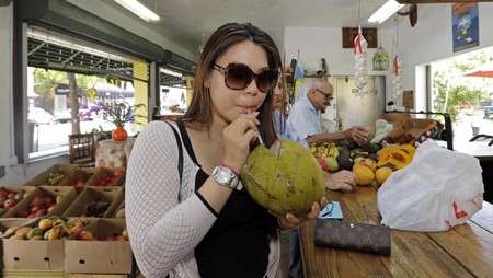 In this photo taken Tuesday, June 9, 2015, Lillian Nguyen, of New York, sips coconut water at a fruit store in the Little Havana area of Miami. (AP Photo/Alan Diaz)