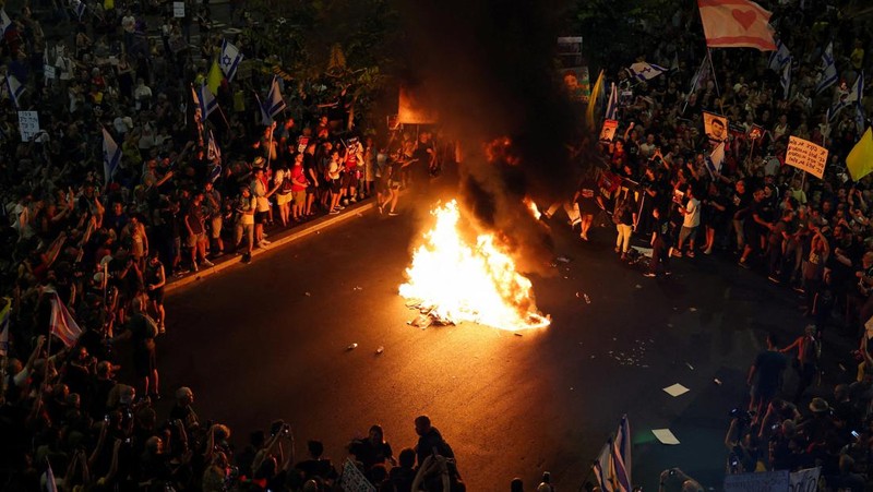 Para demonstran berkumpul di sekitar api unggun selama demonstrasi menentang pemerintahan Perdana Menteri Israel Benjamin Netanyahu dan menyerukan pembebasan sandera di Gaza, di tengah konflik Israel-Hamas, di Tel Aviv, Israel, 7 September 2024. (REUTERS/Florion Goga)