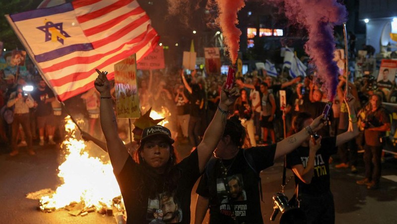 Para demonstran berkumpul di sekitar api unggun selama demonstrasi menentang pemerintahan Perdana Menteri Israel Benjamin Netanyahu dan menyerukan pembebasan sandera di Gaza, di tengah konflik Israel-Hamas, di Tel Aviv, Israel, 7 September 2024. (REUTERS/Florion Goga)