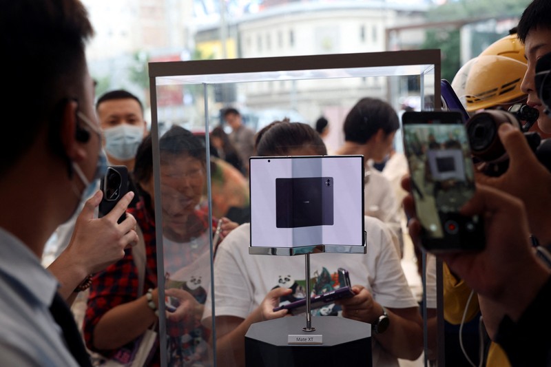 Seorang anggota staf bersiap untuk memamerkan Huawei Mate XT, telepon pintar yang dapat dilipat tiga, di toko utama Huawei di Beijing, Cina, 10 September 2024. (REUTERS/Florence Lo)