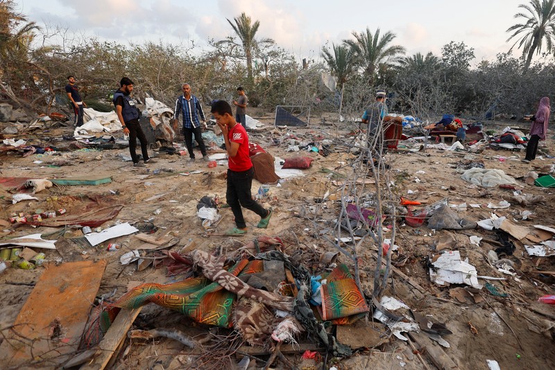 Orang-orang memeriksa lokasi setelah serangan Israel terhadap kamp tenda yang melindungi orang-orang terlantar, di tengah konflik Israel-Hamas, di daerah Al-Mawasi di Khan Younis, di Jalur Gaza selatan, 10 September 2024. (REUTERS/Mohammed Salem)
