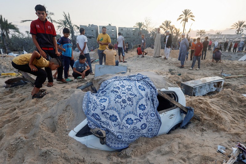 Orang-orang memeriksa lokasi setelah serangan Israel terhadap kamp tenda yang melindungi orang-orang terlantar, di tengah konflik Israel-Hamas, di daerah Al-Mawasi di Khan Younis, di Jalur Gaza selatan, 10 September 2024. (REUTERS/Mohammed Salem)