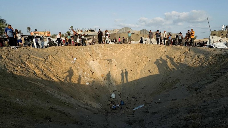 Orang-orang memeriksa lokasi setelah serangan Israel terhadap kamp tenda yang melindungi orang-orang terlantar, di tengah konflik Israel-Hamas, di daerah Al-Mawasi di Khan Younis, di Jalur Gaza selatan, 10 September 2024. (REUTERS/Mohammed Salem)