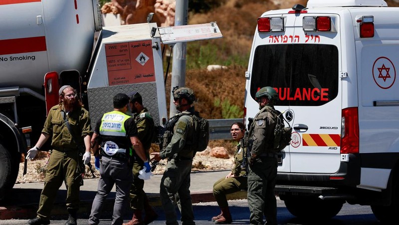 Petugas keamanan dan tanggap darurat Israel bekerja pada lokasi serangan serudukan truk bahan bakar di dekat pemukiman Givat Assaf, dekat Ramallah di Tepi Barat yang diduduki Israel, Rabu (11/9/2024). (REUTERS/Ammar Awad)