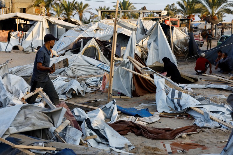 Orang-orang memeriksa lokasi setelah serangan Israel terhadap kamp tenda yang melindungi orang-orang terlantar, di tengah konflik Israel-Hamas, di daerah Al-Mawasi di Khan Younis, di Jalur Gaza selatan, 10 September 2024. (REUTERS/Mohammed Salem)