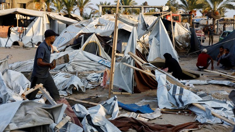 Orang-orang memeriksa lokasi setelah serangan Israel terhadap kamp tenda yang melindungi orang-orang terlantar, di tengah konflik Israel-Hamas, di daerah Al-Mawasi di Khan Younis, di Jalur Gaza selatan, 10 September 2024. (REUTERS/Mohammed Salem)