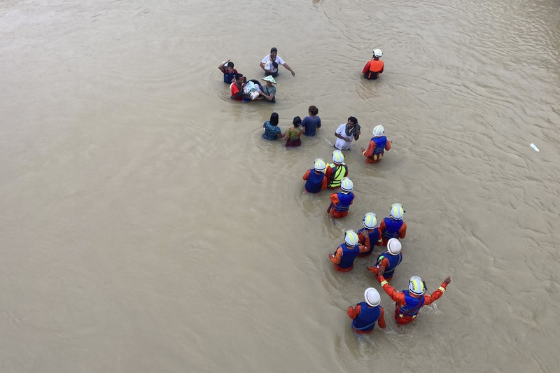 Warga dibantu melewati banjir oleh personel militer di Pyinmana di wilayah Naypyidaw, Myanmar, pada 13 September 2024, menyusul hujan lebat setelah Topan Yagi. (AFP/SAI AUNG MAIN)