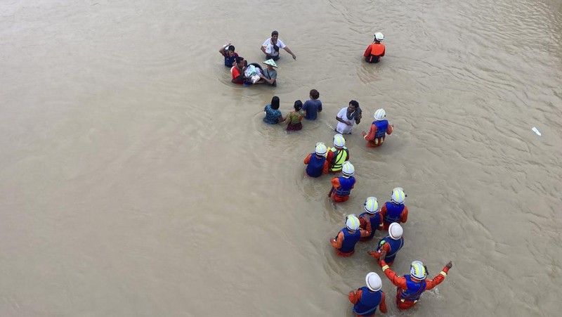 Warga dibantu melewati banjir oleh personel militer di Pyinmana di wilayah Naypyidaw, Myanmar, pada 13 September 2024, menyusul hujan lebat setelah Topan Yagi. (AFP/SAI AUNG MAIN)