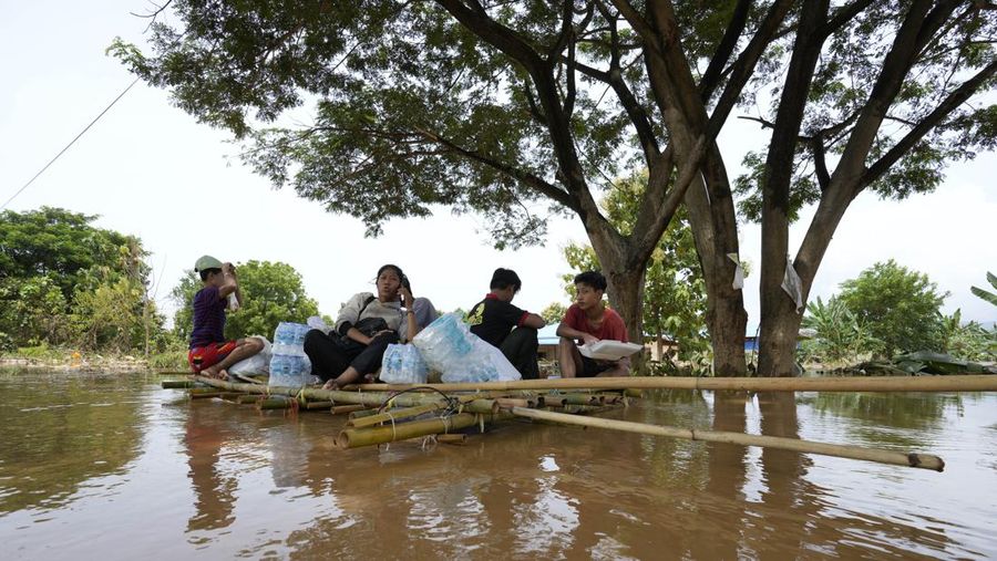 Warga dibantu melewati banjir oleh personel militer di Pyinmana di wilayah Naypyidaw, Myanmar, pada 13 September 2024, menyusul hujan lebat setelah Topan Yagi. (AFP/SAI AUNG MAIN)
