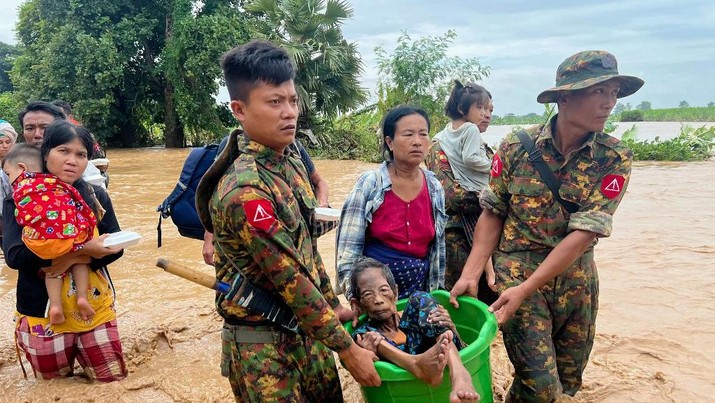 Warga dibantu melewati banjir oleh personel militer di Pyinmana di wilayah Naypyidaw, Myanmar, pada 13 September 2024, menyusul hujan lebat setelah Topan Yagi. (AFP/SAI AUNG MAIN)