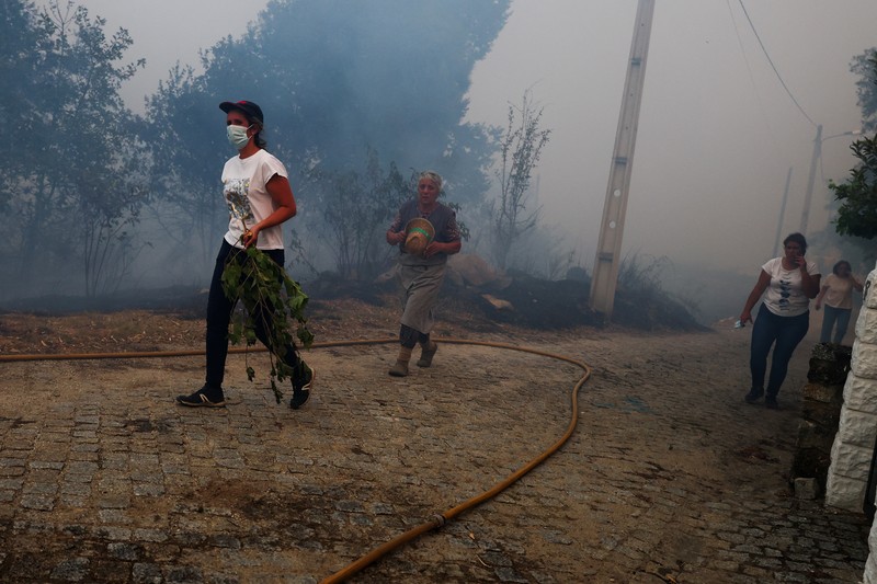 Seorang pria memegang ember selama kebakaran hutan di Nelas, Portugal, 16 September 2024. (REUTERS/Pedro Nunes)