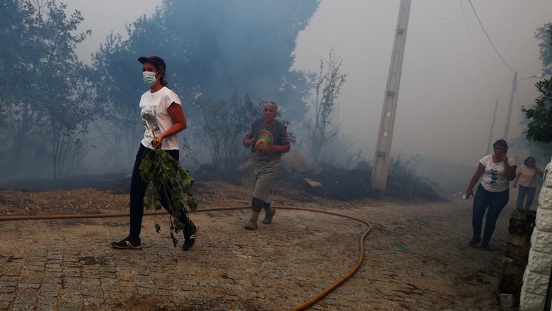 Seorang pria memegang ember selama kebakaran hutan di Nelas, Portugal, 16 September 2024. (REUTERS/Pedro Nunes)