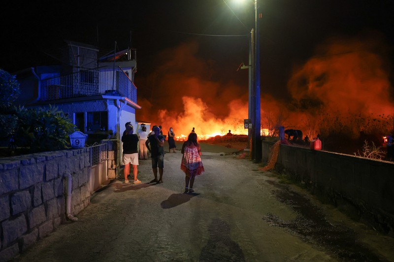 Seorang pria memegang ember selama kebakaran hutan di Nelas, Portugal, 16 September 2024. (REUTERS/Pedro Nunes)