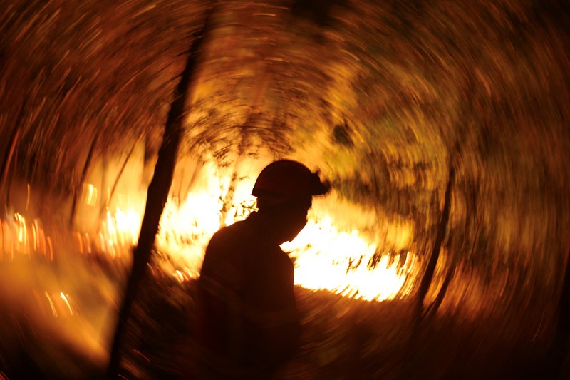 Seorang pria memegang ember selama kebakaran hutan di Nelas, Portugal, 16 September 2024. (REUTERS/Pedro Nunes)