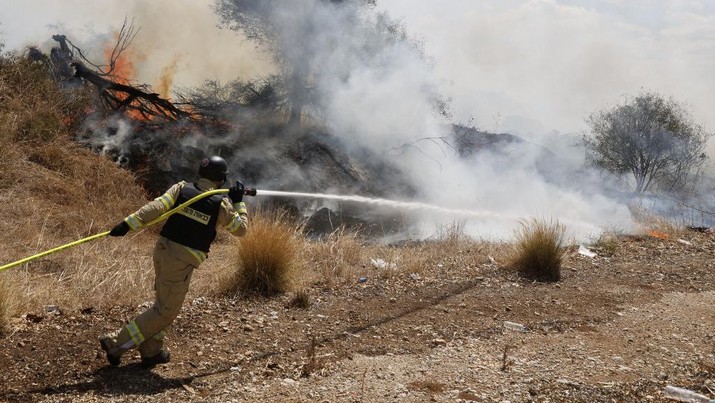 Petugas pemadam kebakaran memadamkan api di sebuah ladang setelah sebuah pesawat tak berawak yang diluncurkan dari Lebanon selatan jatuh di dekat Senir Kibbutz di Galilea Atas di Israel utara pada 16 September 2024. (Photo by Jalaa MAREY / AFP)